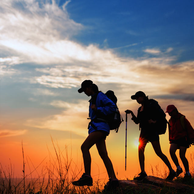 Achievements as depicted by a trio of women hiking against a backdrop of an amazing sunset