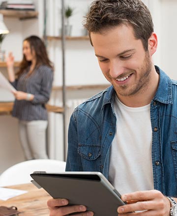 Smiling young man working with a tablet-sized computer
