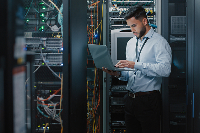 Man looking at computer next to servers. Managed Cloud, with IT support, a cloud solution