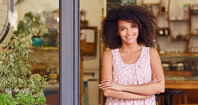 Young female shop owner at the doorway of her storefront