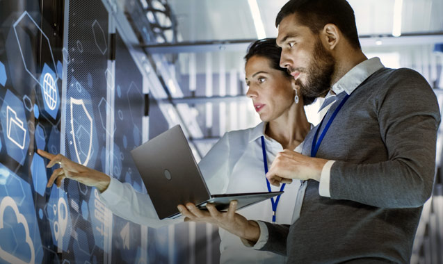 Two network engineers examine a server rack within a data center
