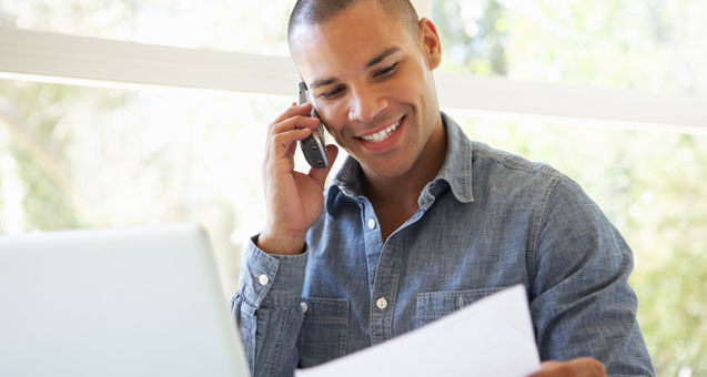 Creative professional fields a call while checking his network-connected workstation