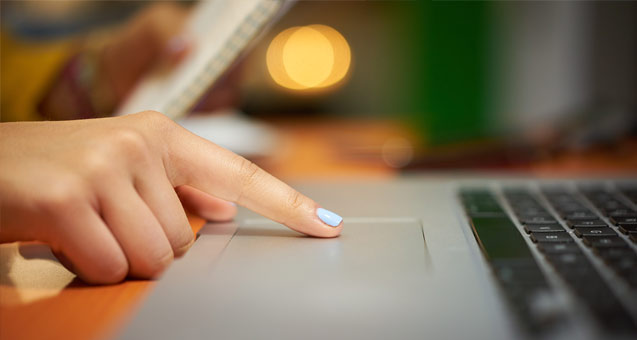 Close-up image of a laptop computer with someone using the finger pad for navigation