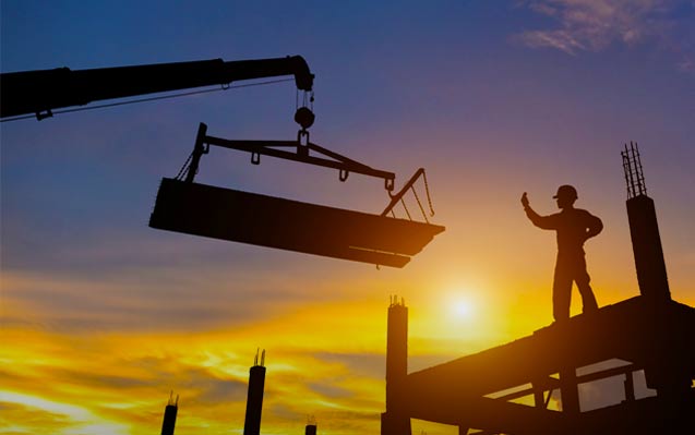 Construction worker guides a crane operator to place his load on a rooftop