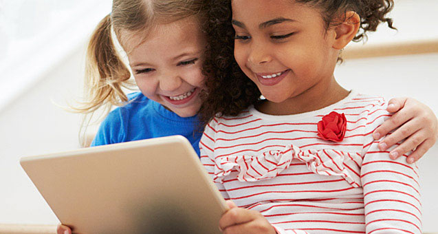 Two young girls playing together with a laptop computer
